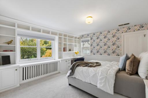 Second bedroom on upper level with built-in shelving and window seat