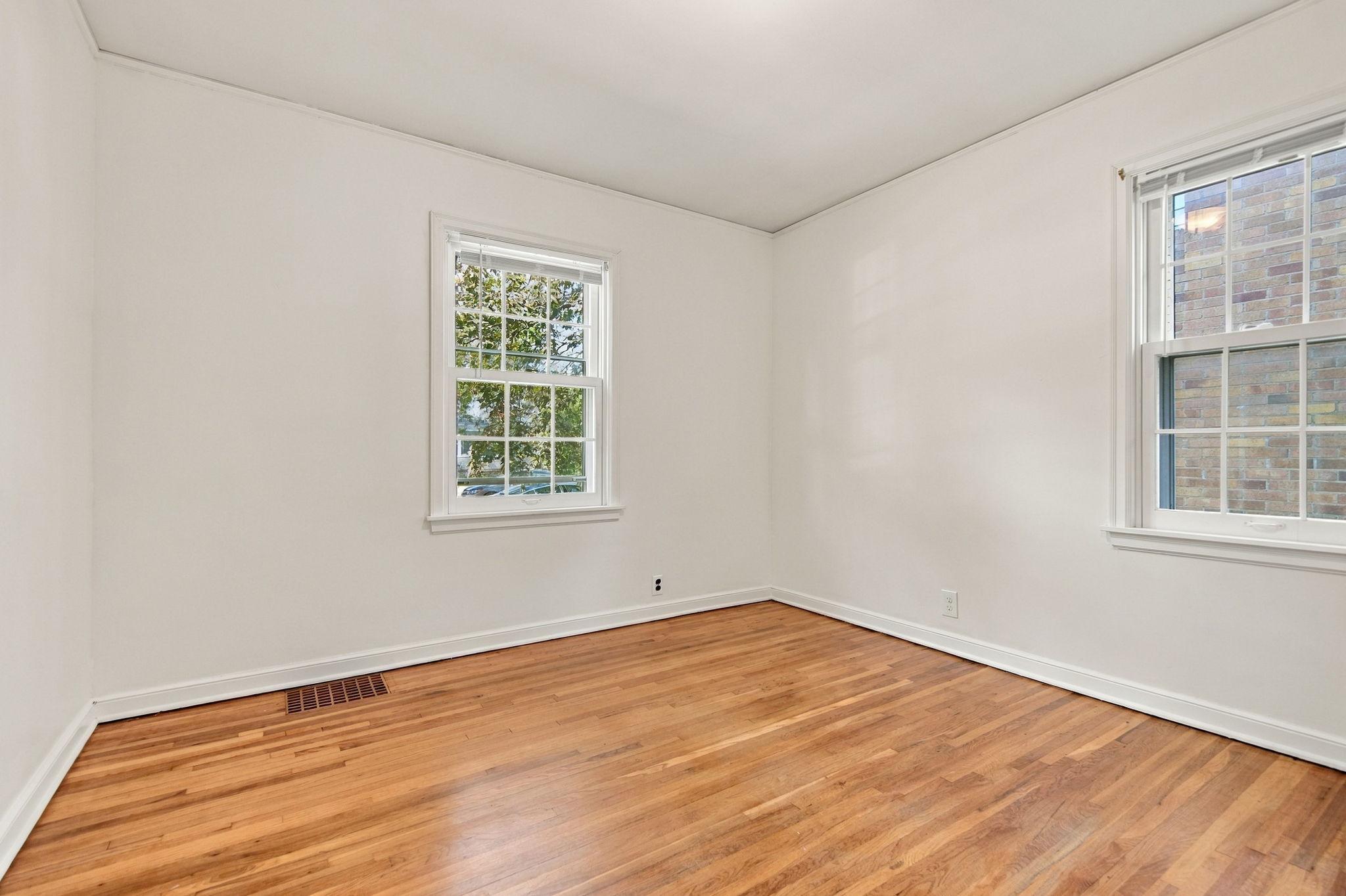 One of two main-floor bedrooms, freshly painted and featuring hardwood floors and abundant natural light.