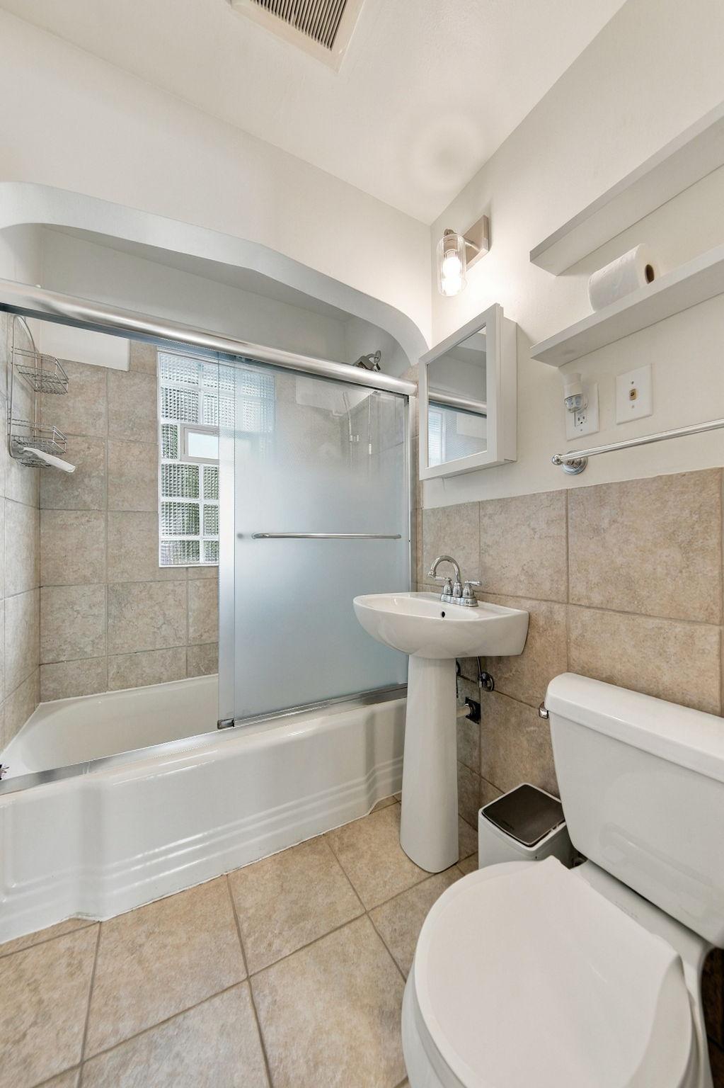 An updated main-floor full bathroom features distinctive glass-block windows