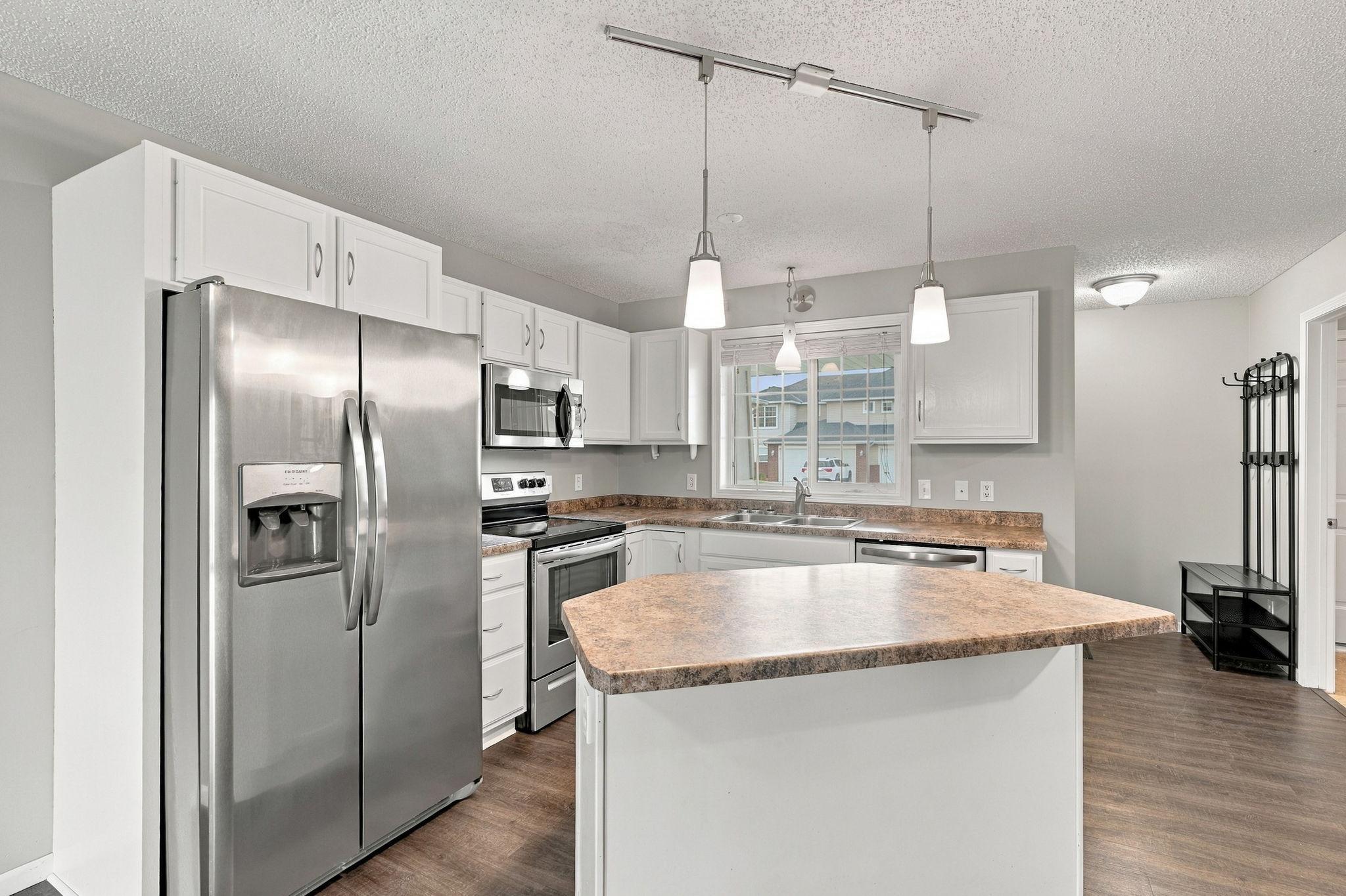 The kitchen offers white cabinetry, stainless steel appliances, and a center island, perfect for meal prep and gathering.