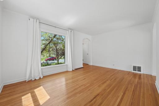 Sun-filled living room with refinished hardwood floors and oversized picture window