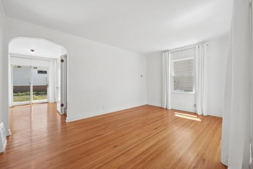 Open flow from living room through arched entry to dining and patio