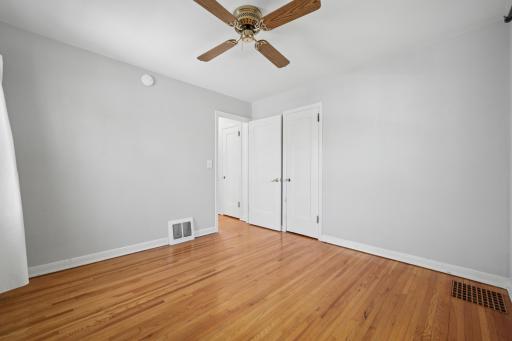 Bedroom with closet built-ins and warm wood floors