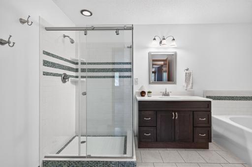 Tiled walk-in shower and tiled tub surround as well as floor. Updated vanity as well