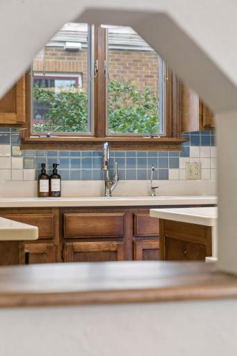 Kitchen sink with reverse osmosis faucet, blue tile backsplash, and window over the counter.