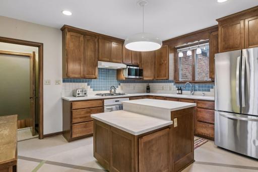 Kitchen with two-tier island, gas cooktop, and blue tile backsplash.