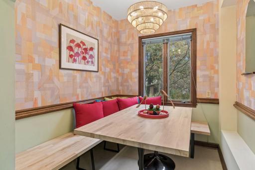 Breakfast nook with built-in banquette, tiered chandelier, and geometric wallpaper.