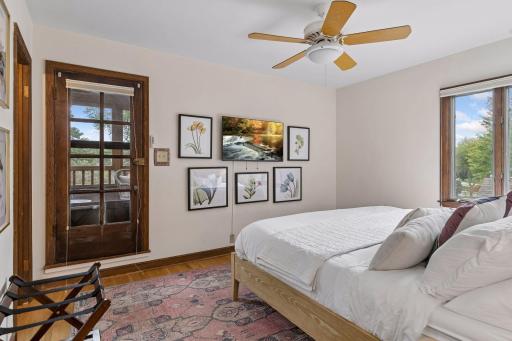 Upper- level 3rd Bedroom with glass-paned door to the screened porch, ceiling fan, and oak floors.