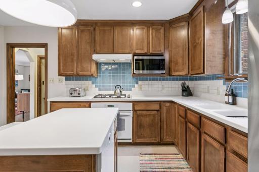 Kitchen with gas cooktop, built-in microwave, and blue and white tile backsplash.