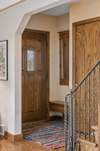 Front entry with leaded glass door, oak trim, and staircase with metal balusters.