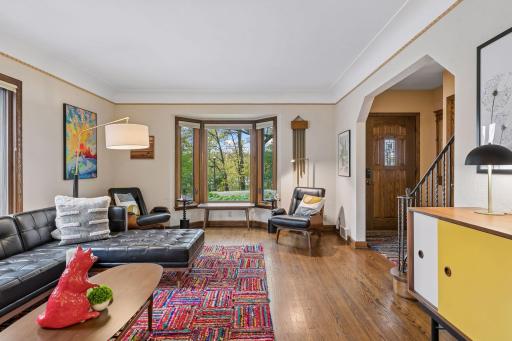 Living room with bay window, oak trim, and arched opening to the front entry and staircase.