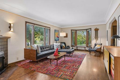 Living room with oak floors, coved ceiling, and two banks of windows.