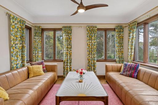 Sunroom with windows on three sides, oak trim, and ceiling fan.