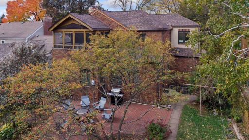 Herringbone brick patio and backyard gardens seen from above, with the screened porch at the rear of the home.