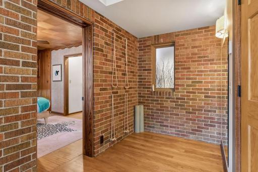 Exercise and yoga area with exposed brick walls, wood floors, and natural light from a side window.