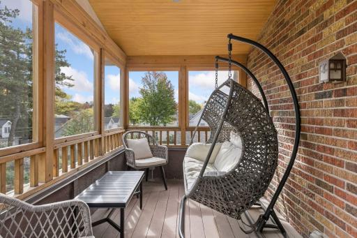 Screened porch off of 3rd upper-level bedroom built in 2014 with wood plank ceiling, exposed brick wall, and treetop views.