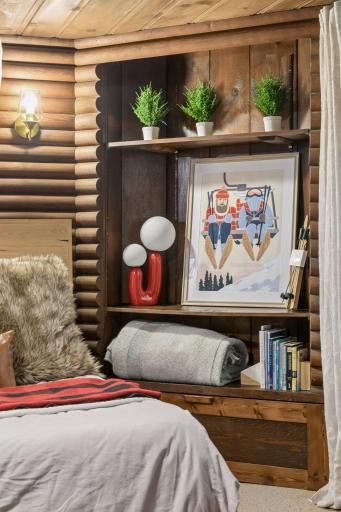 Log cabin bedroom detail with log walls and built-in display shelving.