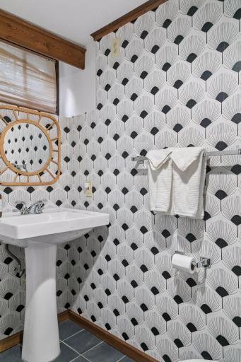 Lower-level 3/4 bath with pedestal sink and geometric patterned walls.