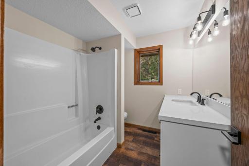 The bathroom has been renovated with a new vanity, toilet, lighting, and mirror.