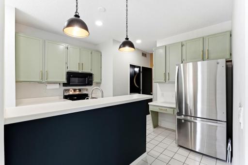 Complete with a convenient breakfast bar and modern pendant lighting, this kitchen features beautifully painted cabinetry and a stainless refrigerator, combining style with everyday function.