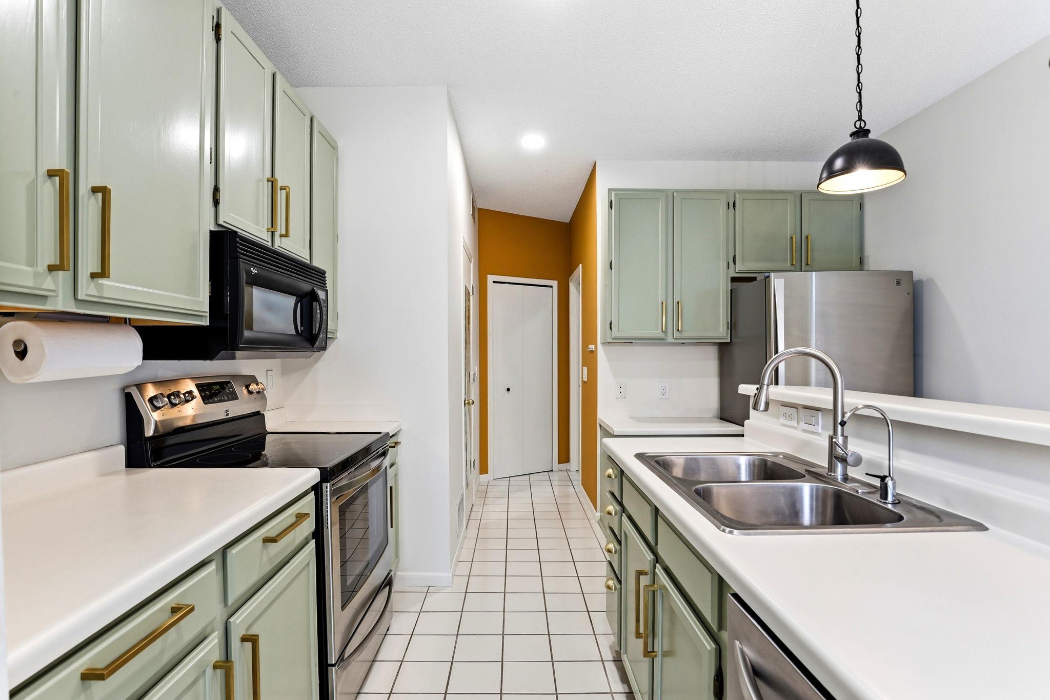 he well-appointed kitchen boasts professionally painted cabinetry with elegant gold hardware, ample counter space, tile flooring, and a suite of stainless steel appliances.
