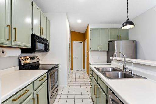 he well-appointed kitchen boasts professionally painted cabinetry with elegant gold hardware, ample counter space, tile flooring, and a suite of stainless steel appliances.
