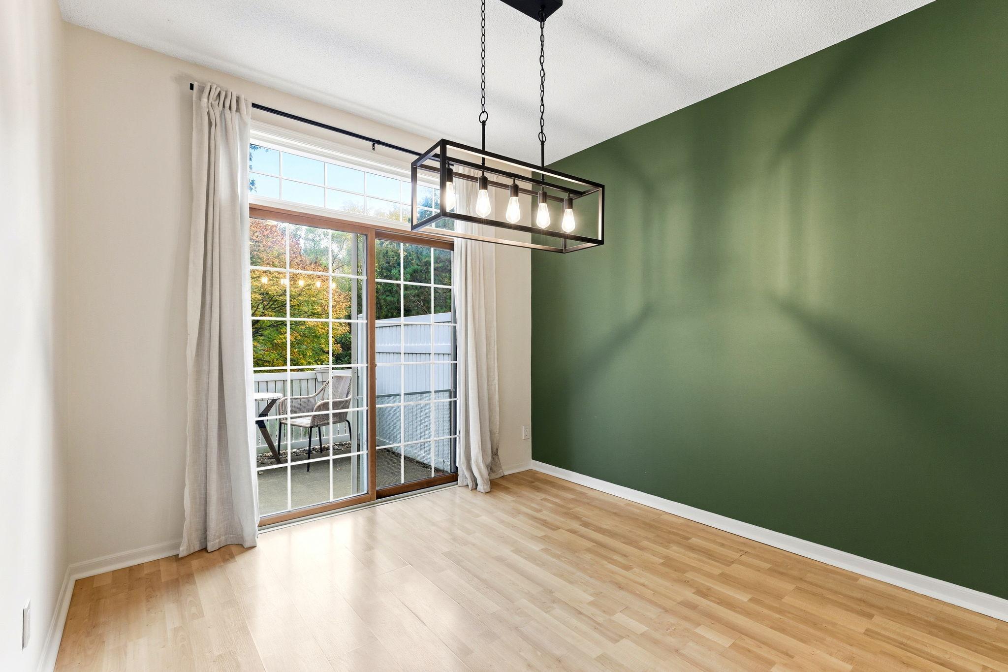 The bright dining space features a modern chandelier, fresh professional paint, and sliding glass doors that lead directly to the private patio, blending indoor and outdoor living seamlessly.