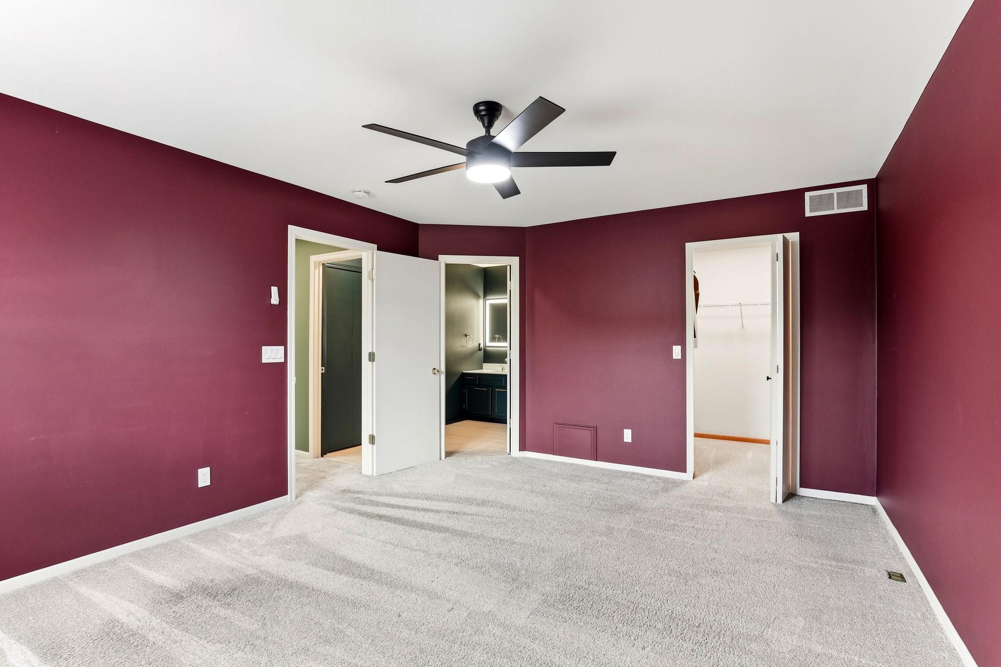 The primary bedroom offers a rich color, a modern ceiling fan, and direct access to a spacious walk-in closet and the adjacent full bathroom for effortless daily routines.