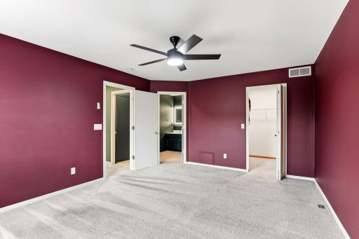 The primary bedroom offers a rich color, a modern ceiling fan, and direct access to a spacious walk-in closet and the adjacent full bathroom for effortless daily routines.