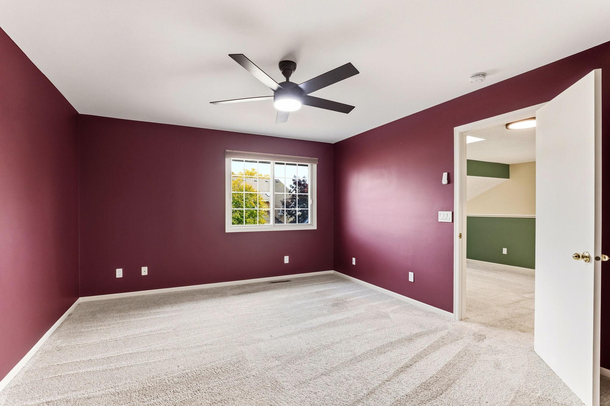The primary bedroom offers a rich color, a modern ceiling fan, and direct access to a spacious walk-in closet and the adjacent full bathroom for effortless daily routines.