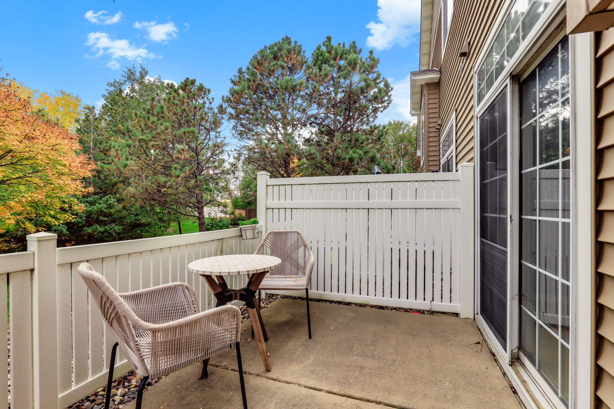 This secluded patio provides a perfect outdoor retreat for morning coffee or evening relaxation. The white fencing ensures privacy while allowing you to enjoy the surrounding mature pine trees and vibrant foliage.