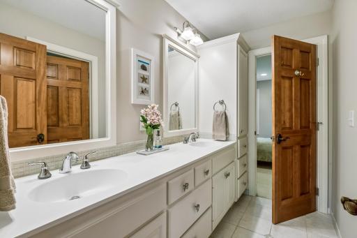 Jack and Jill bathroom has tiled floors, double vanity plus private tub/shower with window and commode