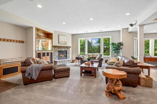 Handsome lower level family/media room boasts 10' ceilings, real stone gas fireplace, surround sound and more windows!
