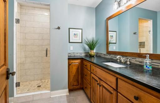 Custom bathroom has soapstone counters, floor-to-ceiling tiled shower with glass door
