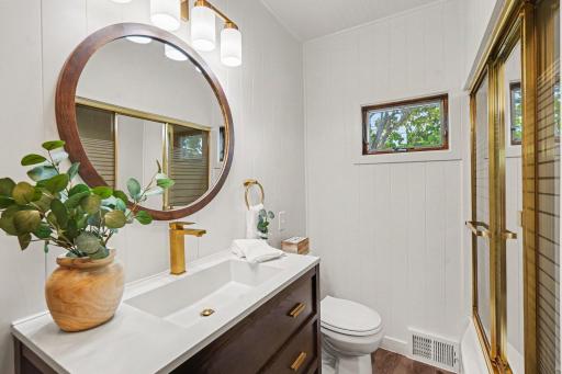 UPDATED MAIN LEVEL BATHROOM WITH NEWER FLOORING, NEWER LIGHTING AND FIXTURES, VANITY AND WATERFALL FAUCET