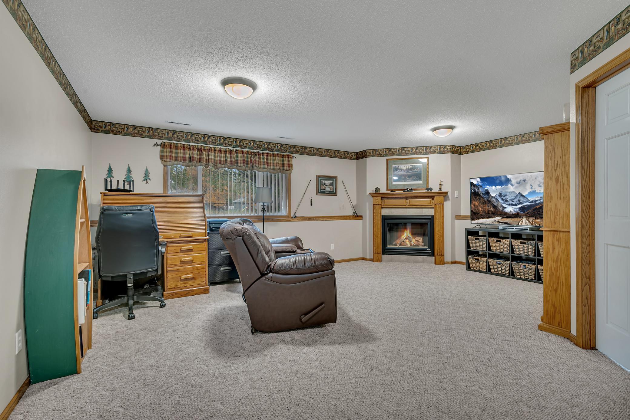 The family room is highlighted by a gas fireplace with a wood mantel, tiled surround, and decorative wood pillars.