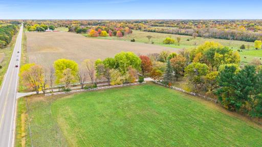A picturesque entrance to the established homesite off Constance Boulevard NE, with a tree-lined driveway surrounded by mature trees and scenic countryside