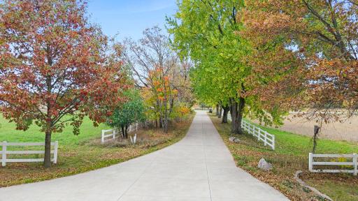Mature trees and established landscaping line the driveway, providing convenient access to the property's residential and agricultural improvements