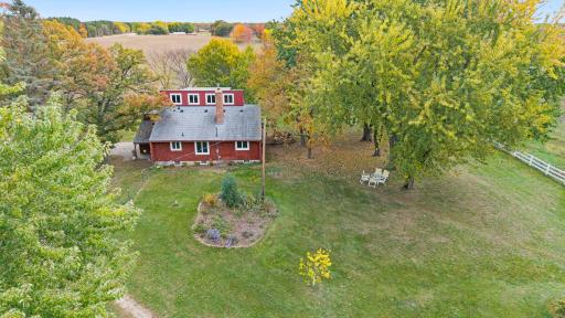 A bird's-eye view of the residential portion of the property, showcasing its wooded surroundings and separation from the agricultural fields