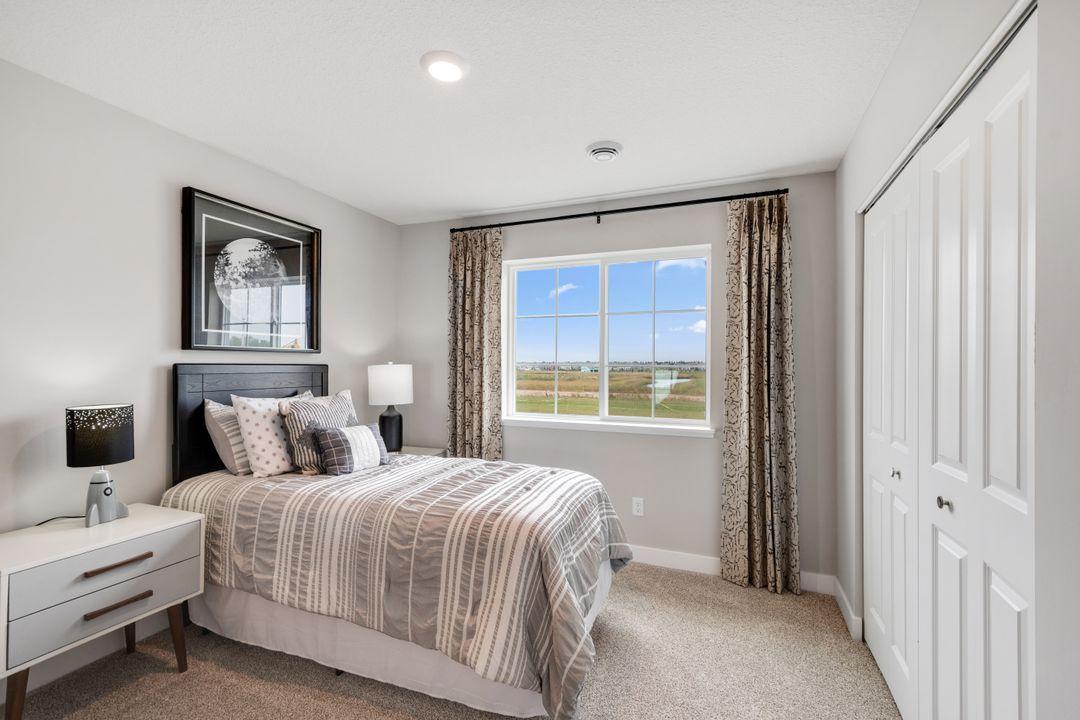 Both upper level bedrooms feature large windows creating bright spaces. Photo of model home. Colors and finishes may vary.