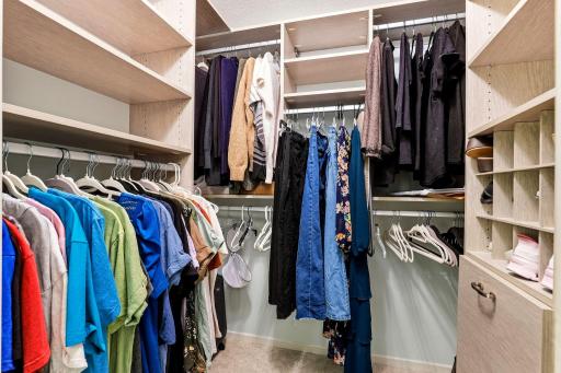 Spacious walk-in closet featuring custom built-in shelving, multiple hanging areas, and abundant storage.