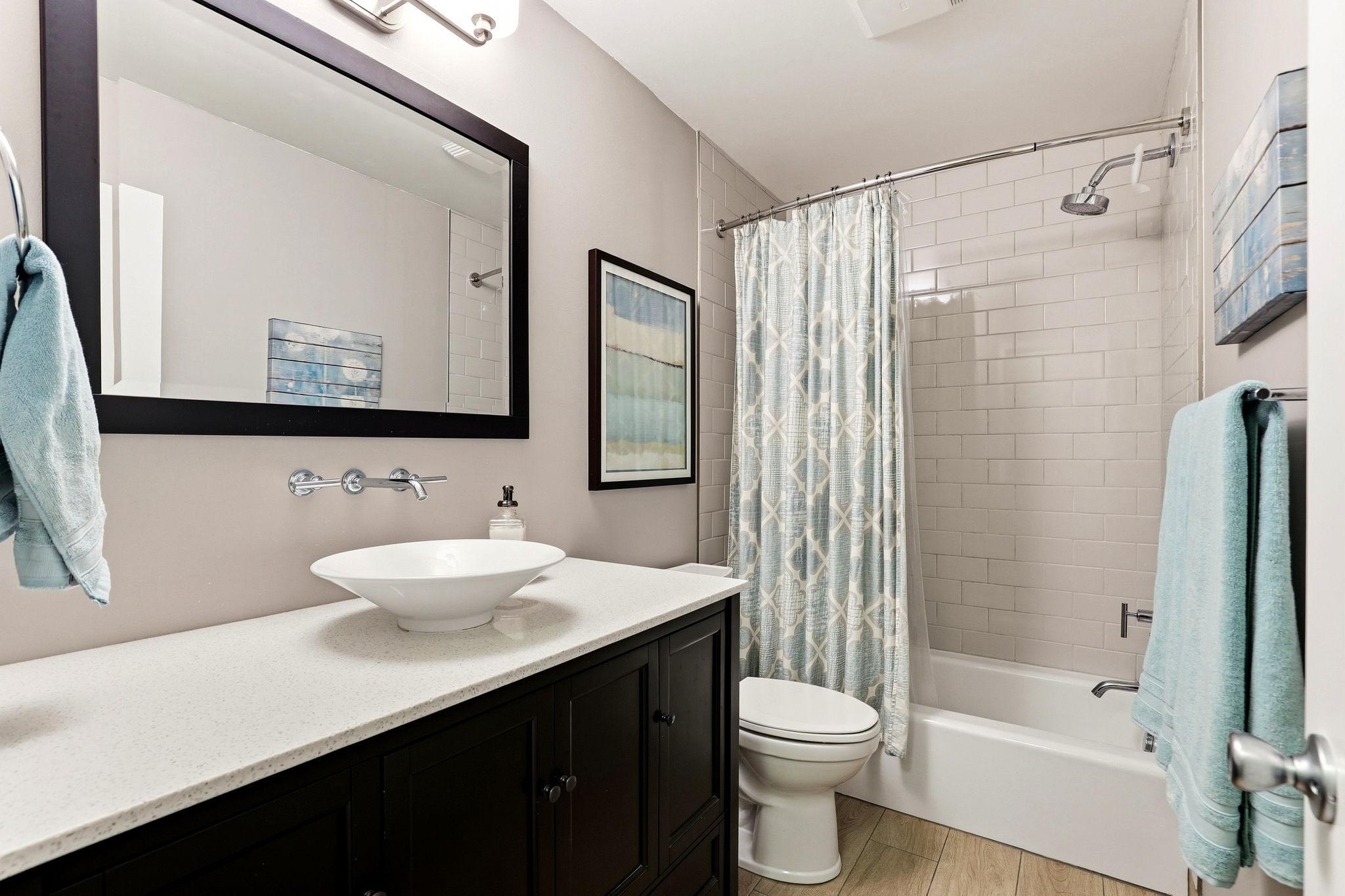 Updated second full bath featuring a modern vessel sink, spacious vanity, and tiled tub/shower surround.