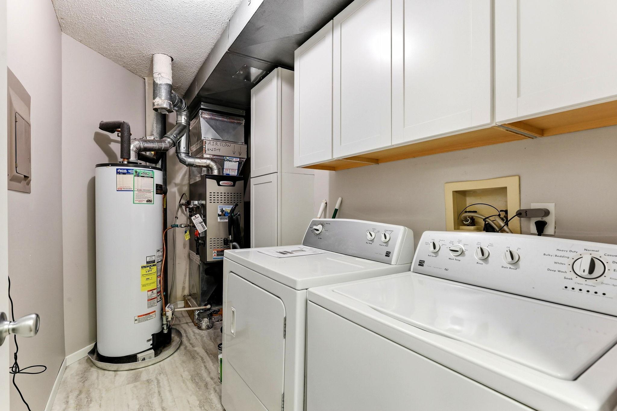 Convenient in-unit laundry room with full-size washer and dryer, built-in cabinetry, and additional storage space.
