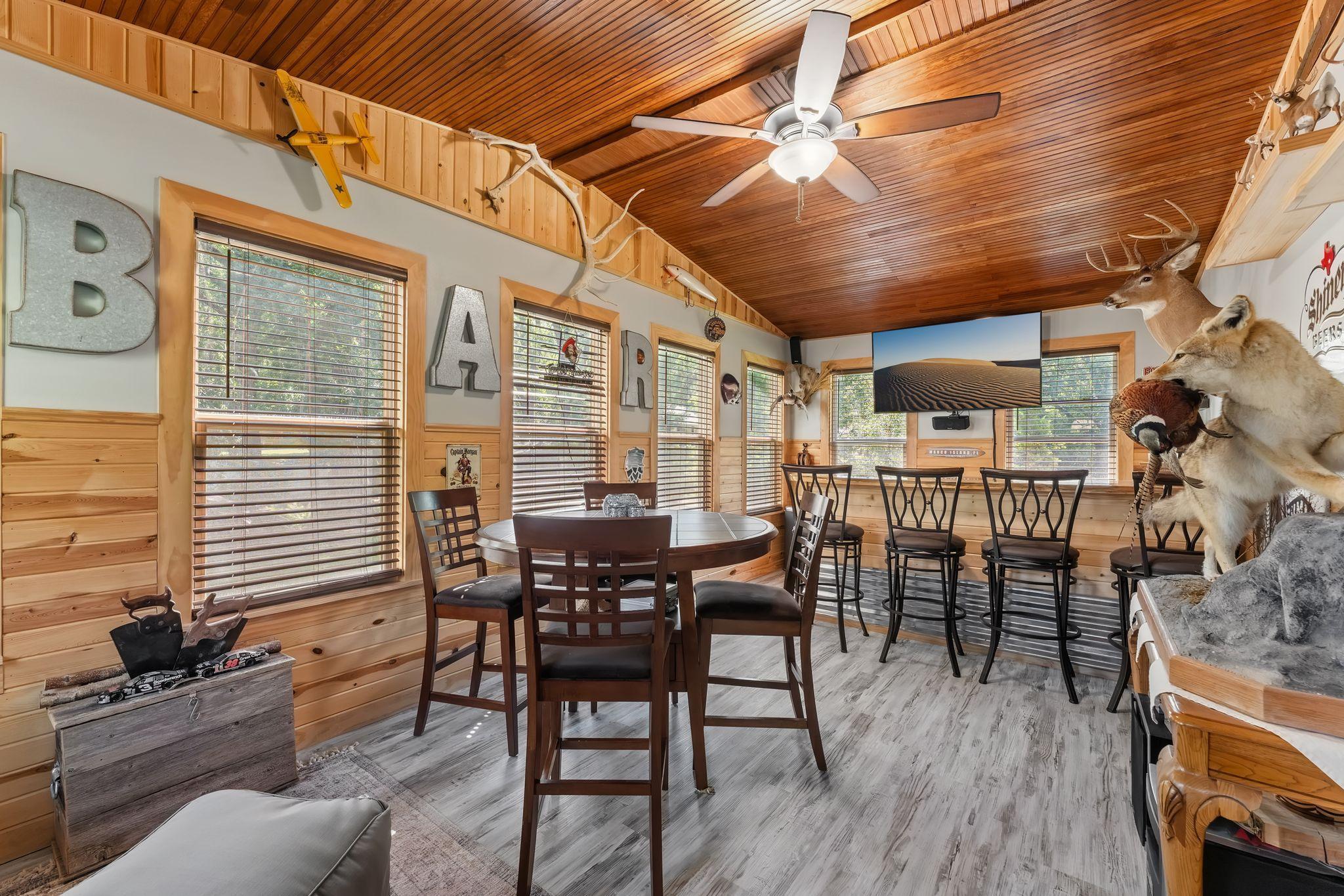The added porch and bar area creates a wonderful bonus entertaining space! With a warm wood ceiling, built-in bar seating, dining space, and plenty of natural light, this versatile area is ready for everything from game nights to gatherings!
