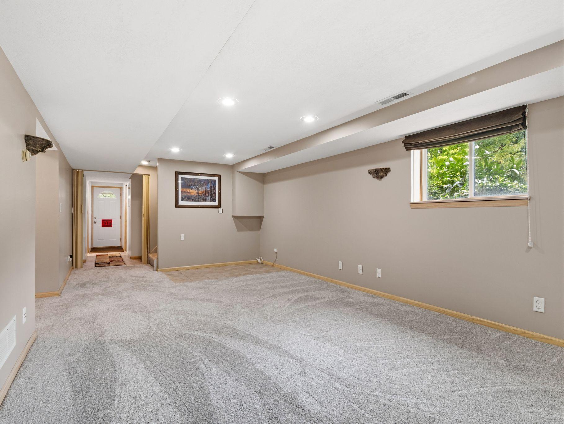 A private exterior entrance provides convenient access to the spacious lower level, offering a great setup for a home office or potential business use. The open layout, recessed lighting, and natural light create a comfortable and versatile space.
