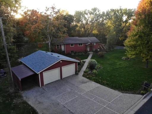Beautifully maintained outdoor space welcomes you with a lush, expansive lawn, mature trees, and thoughtfully designed landscaping. A curved walkway leads to the home, surrounded by colorful plantings and greenery.