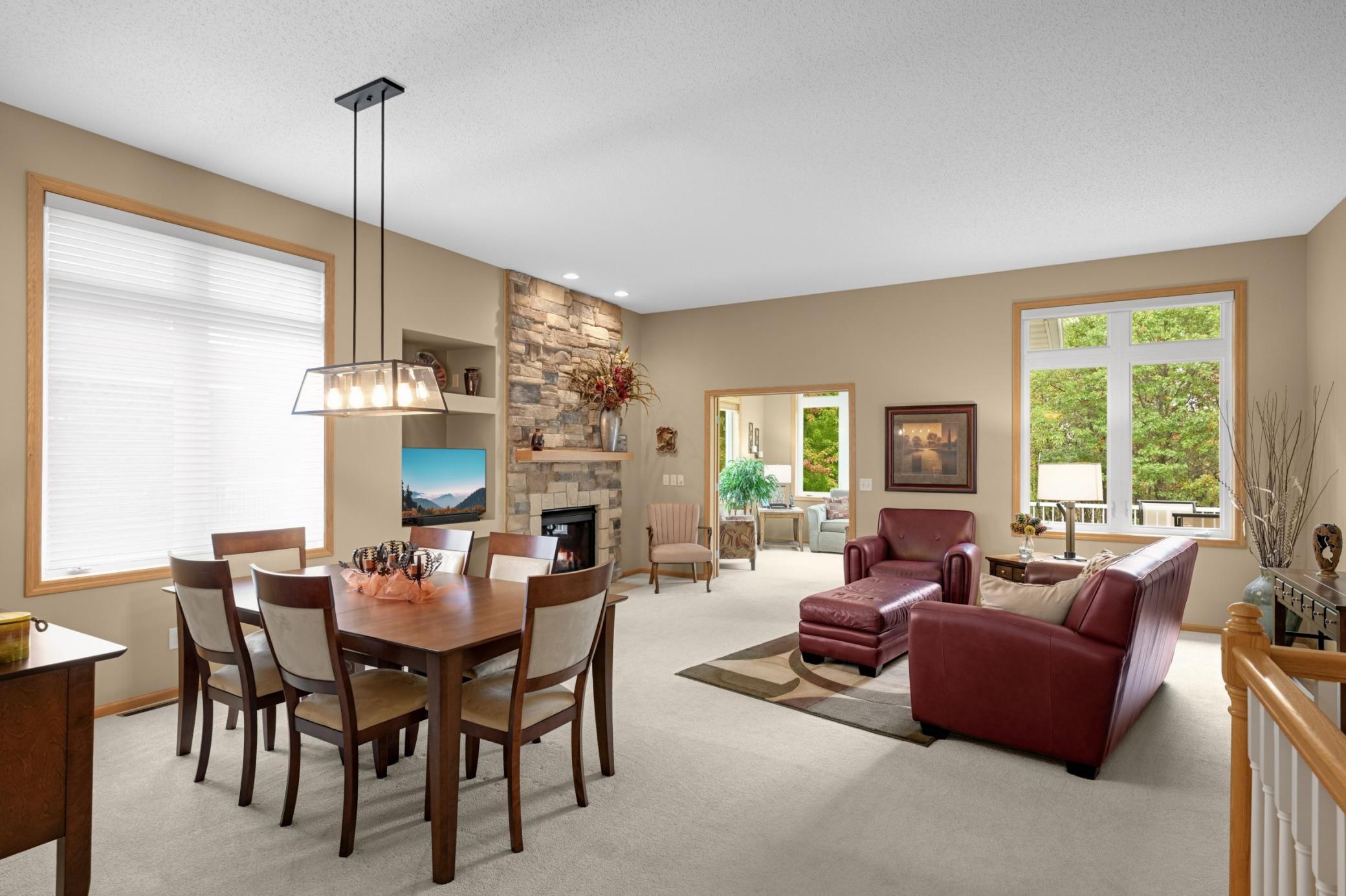 Spacious open living area with room for both a full dining table and comfortable seating. The floor-to-ceiling stone Gas Fireplace creates a beautiful focal point, while the large windows bring the outdoors in.