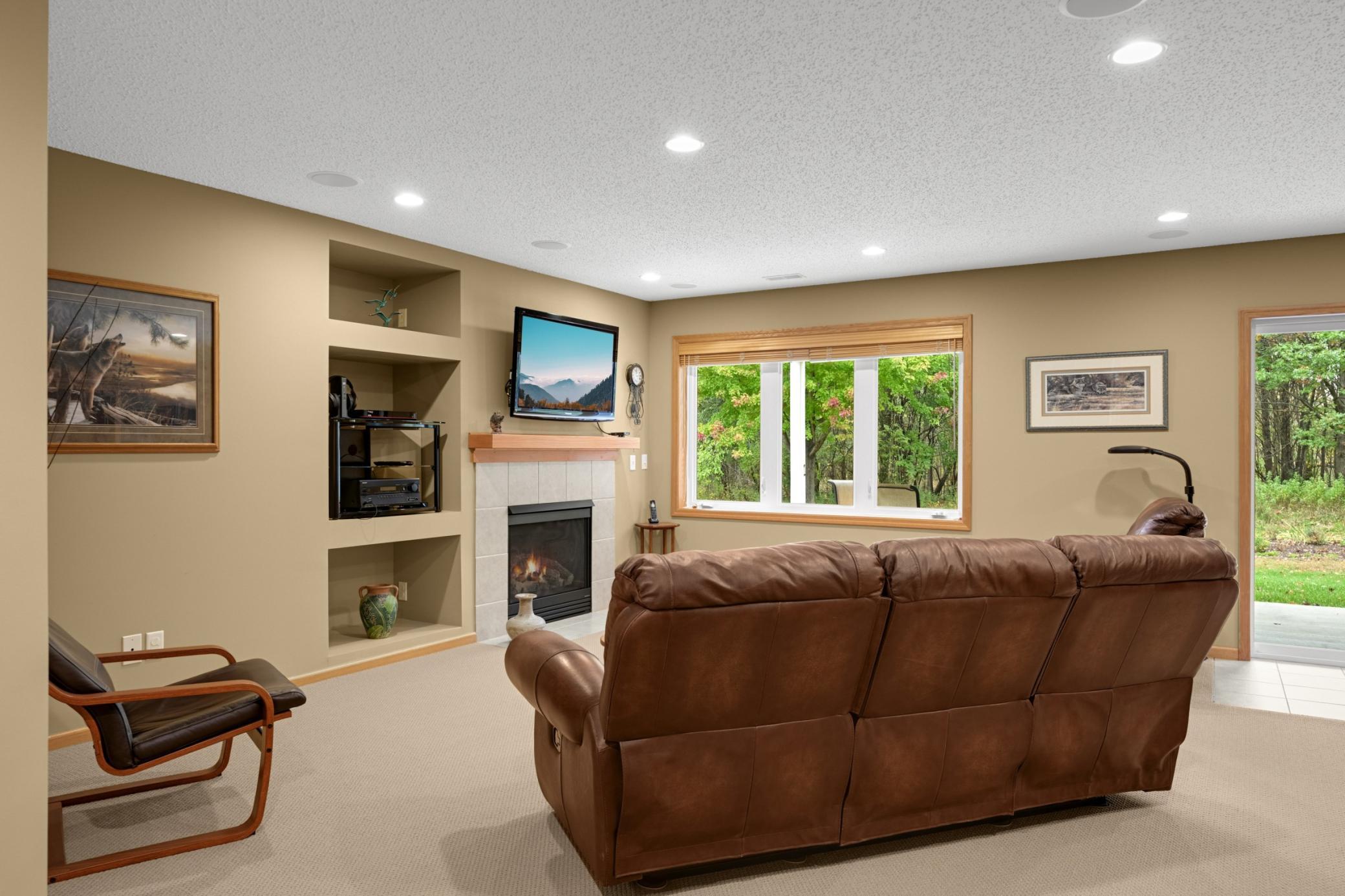 The finished walkout Lower Level offers a spacious Family Room with a second Gas Fireplace, built-in display shelves and large windows overlooking the wooded surroundings. A great place for movie nights or relaxing!