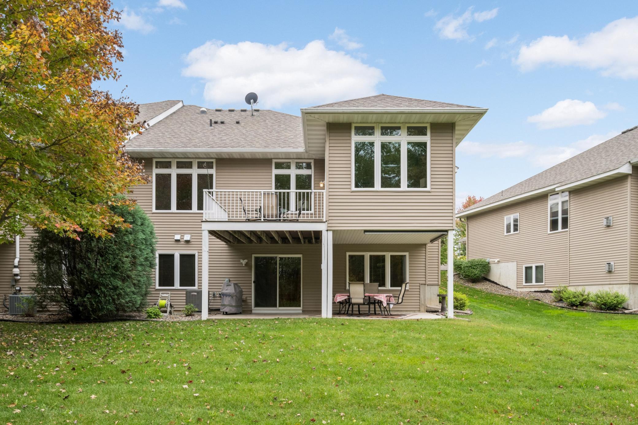 A look at the back of this beautiful twin home shows the upper Deck, covered lower Patio and large windows that bring the outdoors in. The finished walkout Lower Level adds so much versatility to this home!