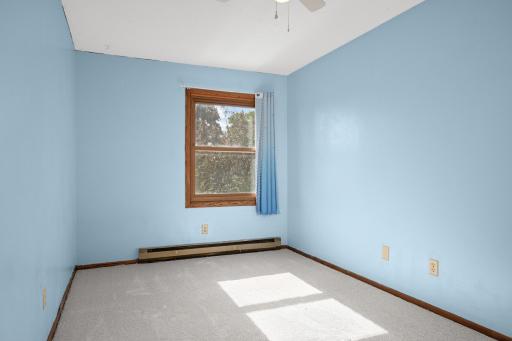 Second upper-level bedroom with a window and soft carpeting.
